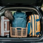 Prtljažnik automobila pun prtljaga, uključujući kofer, ruksake i pletenu korpu, pripremljen za putovanje do najlepših mesta u Srbiji.