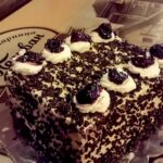 Tradicionalna torta u poslastičarnici Pelivan u Beogradu, prekrivena čokoladnim mrvicama i ukrašena šlagom i višnjama.