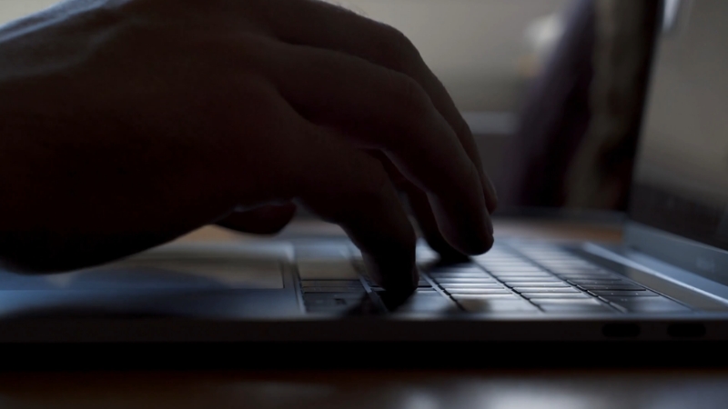 Ruka na tastaturi laptopa prikazuje unos podataka i pripremu dokumenata za prijavu promene šifre delatnosti u firmi