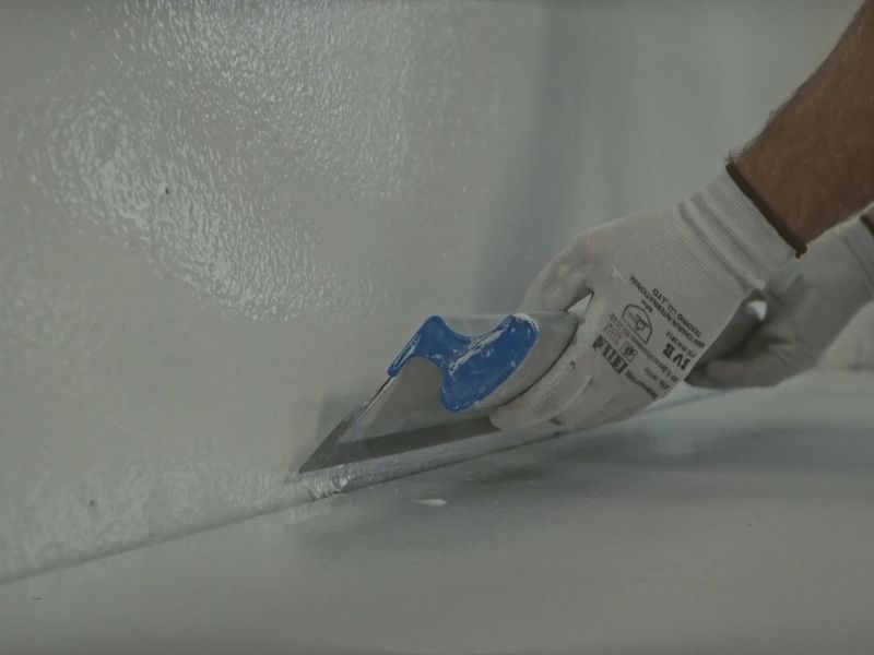 osoba nanosi hidroizolacioni premaz na zid