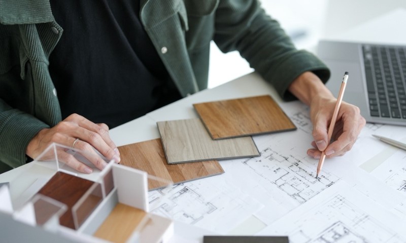 Osoba pregleda arhitektonske planove za stolom