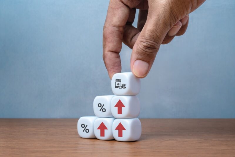 Ruka slaže kockice sa simbolima rasta i procenta kao prikaz finansijskog napretka