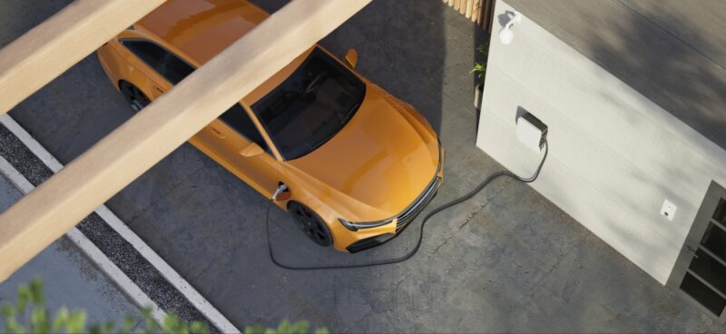 Električni automobil povezan na kućni pametni EV punjač postavljen na spoljašnjem zidu objekta.