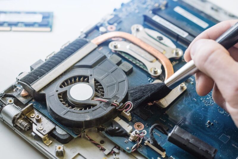 Čišćenje prašine sa ventilatora i rashladnog sistema otvorenog laptopa pomoću meke četkice
